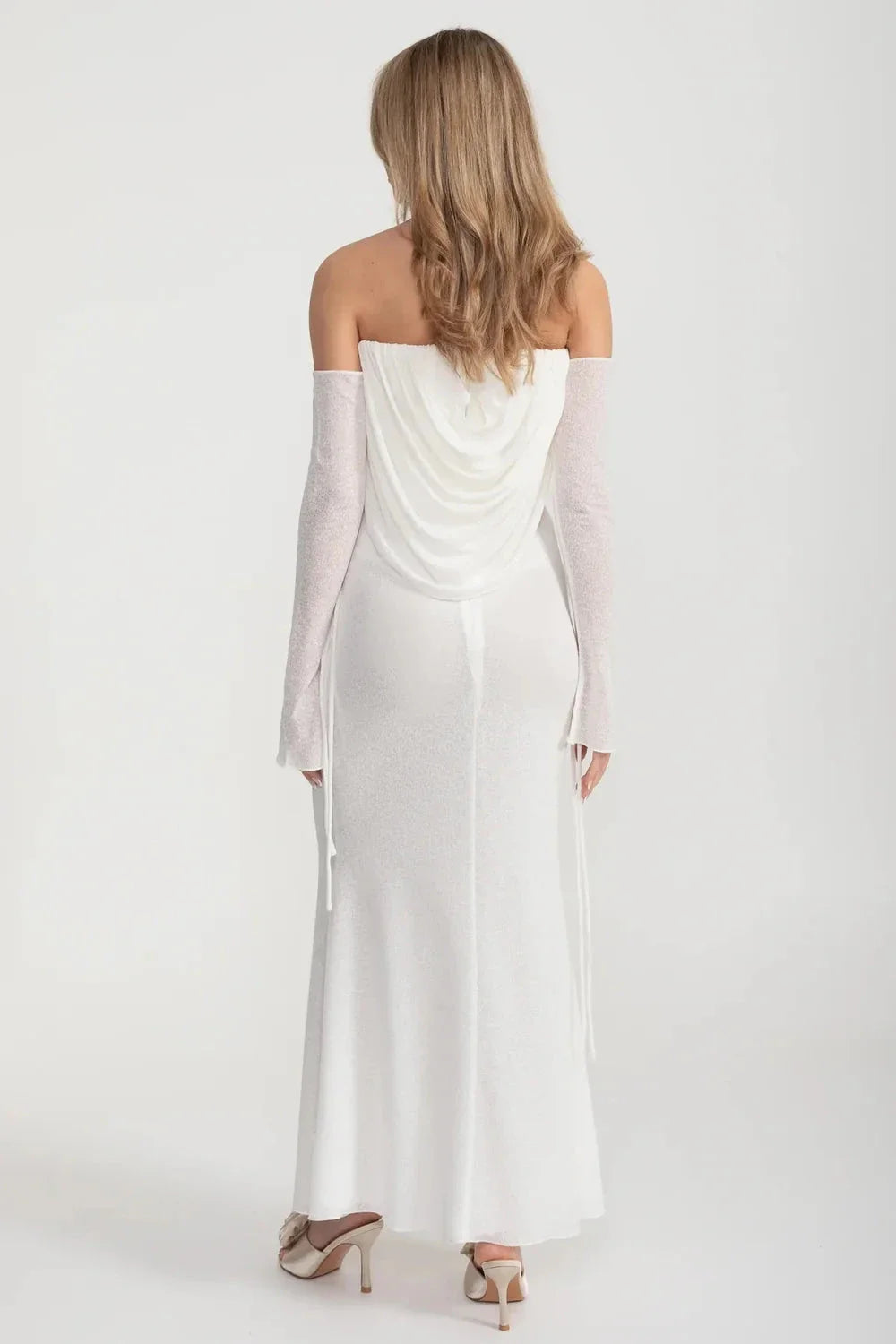 An elegant, flowing white dress with long sleeves, a draped bodice, and a rose embellishment in the center.