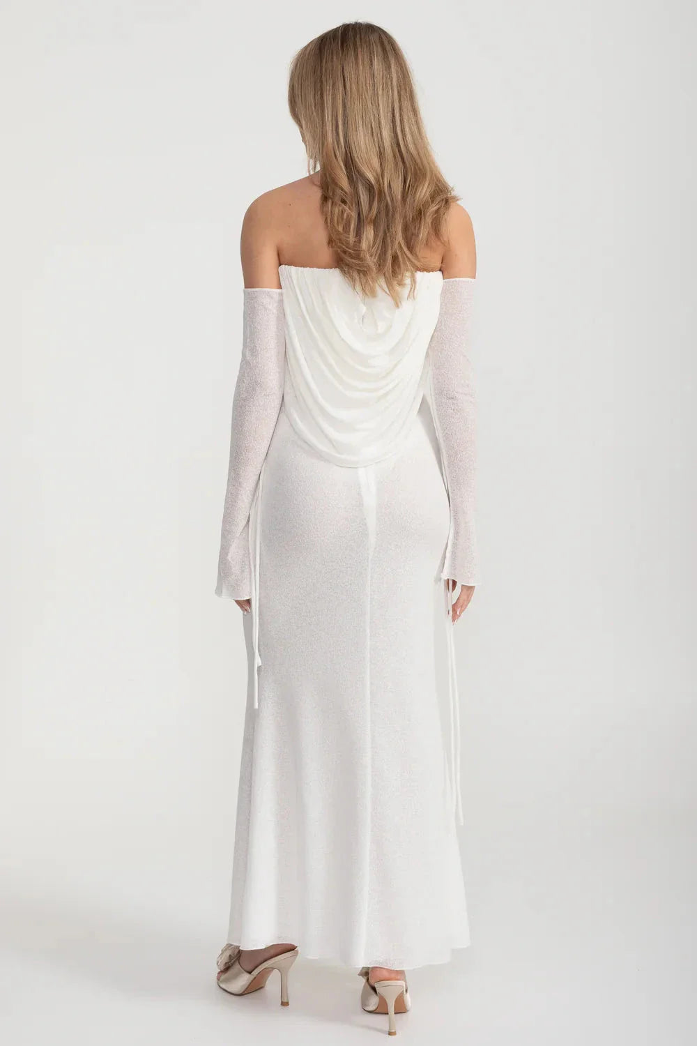 An elegant, flowing white dress with long sleeves, a draped bodice, and a rose embellishment in the center.